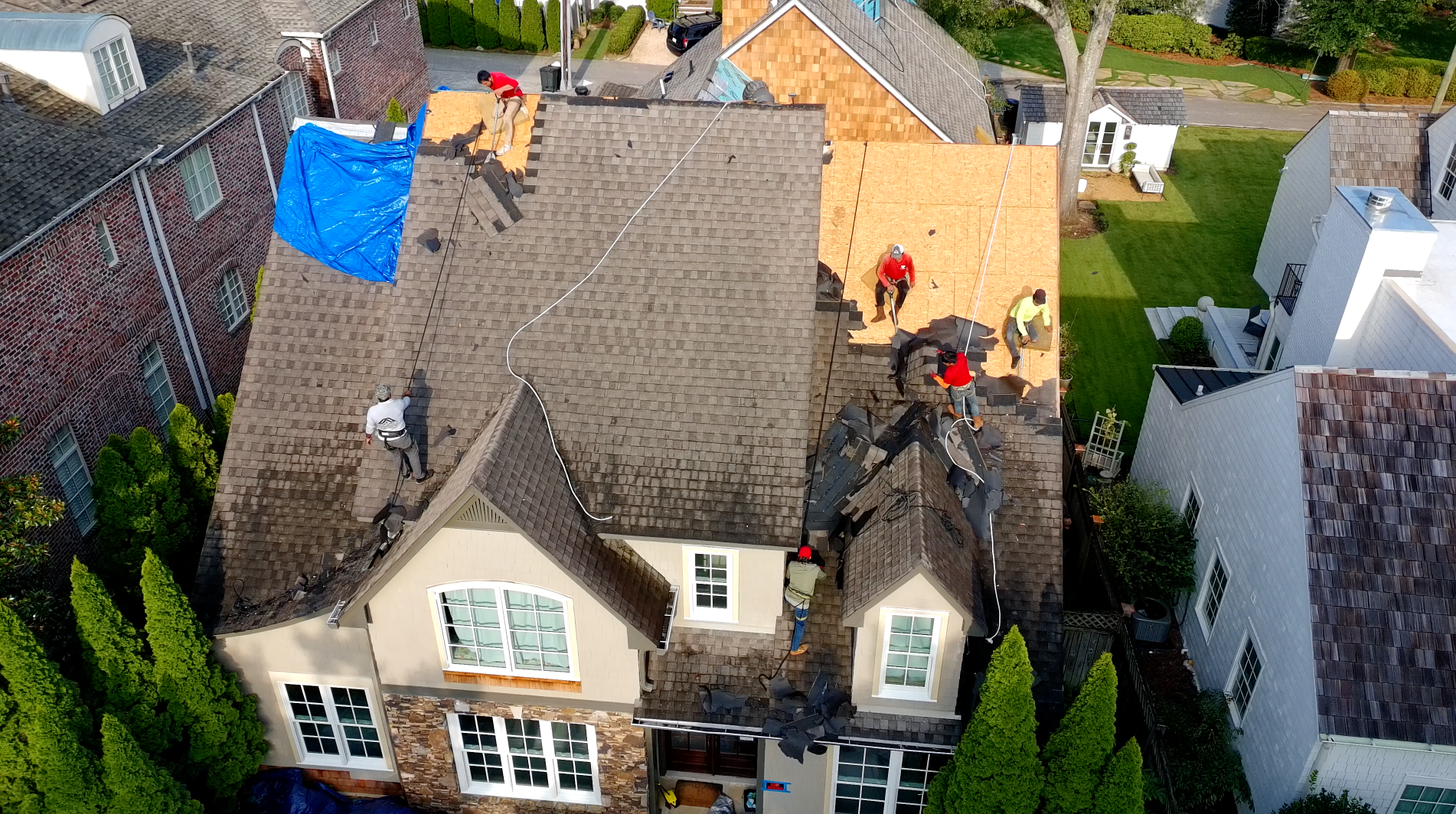 BLW Roofing crew tearing off shingles on a two-story Birmingham home, with safety lines and decking exposed