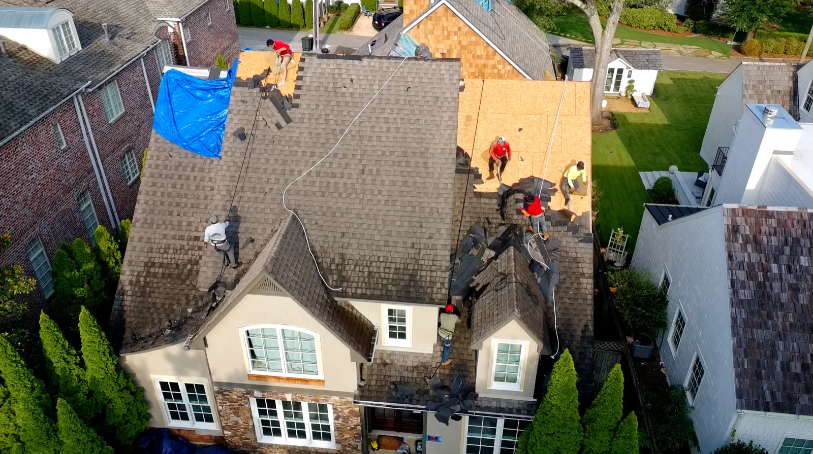 BLW Roofing crew tearing off shingles on a two-story Birmingham home, with safety lines and decking exposed